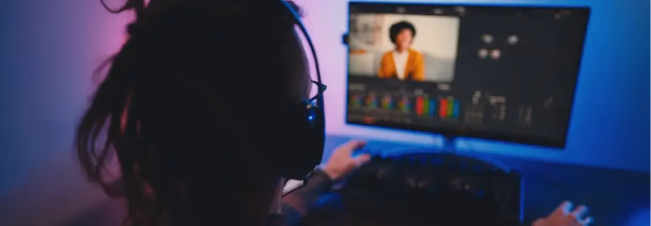 blog_repurposing_man-video-editor-wearing-headphones-sits-at-computer-with-backlight-looks-in-monitor